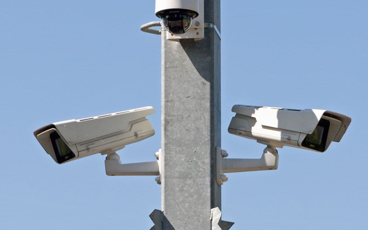Pole-mounted PTZ and box CCTV cameras against a clear blue sky in Paphos